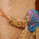 A woman, probably as old as the mud brick wall she sits against, tells stories of her youth from days long past