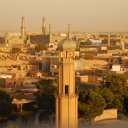 A sunset view of the old city center of Herat with the Jama Mosque in the background. In the foreground are the minarets of another mosque