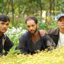 Three brothers pose in front of their carefully maintained flower gardens