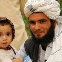 A proud and smiling Pashtun tribesman poses with his little daughter