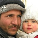 Anxiety, maybe resignation to his situation reflect in this dad\'s face, as he holds his innocent child tightly