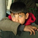 Inside a shop, a boy watches me intently as I looked at wool hats to wear against the bitter cold outside