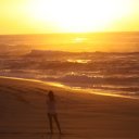 Woman taking photo of sunset, Oahu beach
