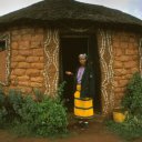 These small one room huts are known as \'rondavels\' and house an entire family. The door and windows are framed nicely with pebbles set in the dried mud brick