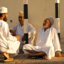 Men with traditional Omani tunics and hats gather for an early morning chat