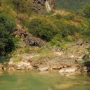 A waterfall tumbles down a limestone cliff face in a canyon rendered green by the monsoon from the Indian Ocean