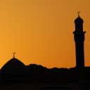 The ubiquitous dome and minaret of a mosque silhuetted in the setting sun