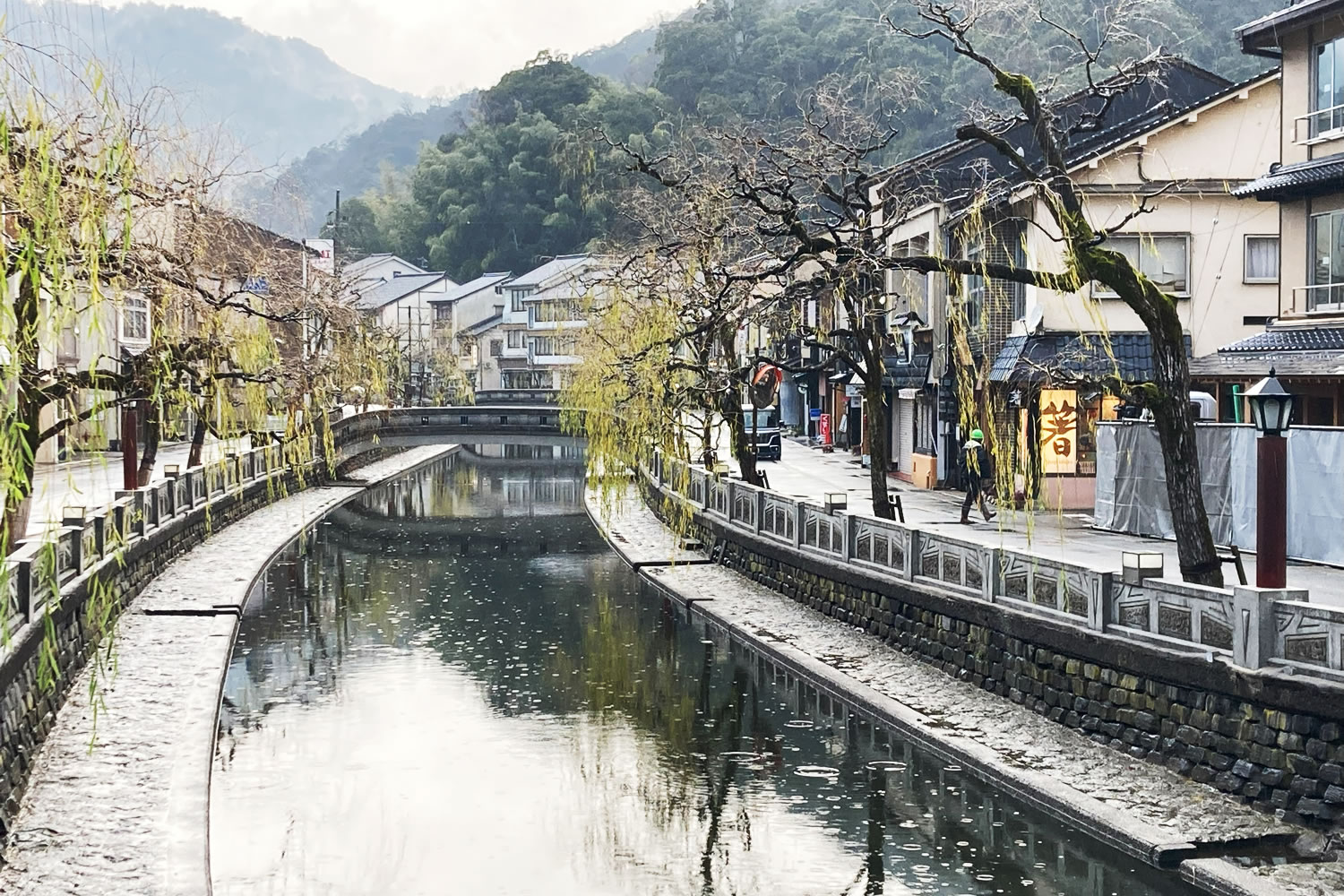 A peaceful riverside scene with willow trees in Kinosaki Onsen, Japan