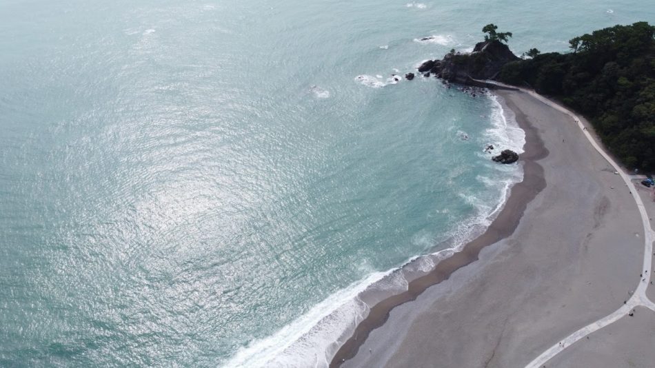 Aerial view of a crescent-shaped beach with turquoise water along Kochi's Pacific coastline, Japan