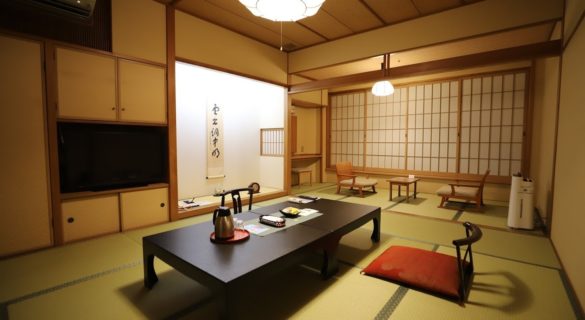 Traditional Japanese ryokan room with tatami floors, calligraphy scroll, and low table in Kochi, Japan
