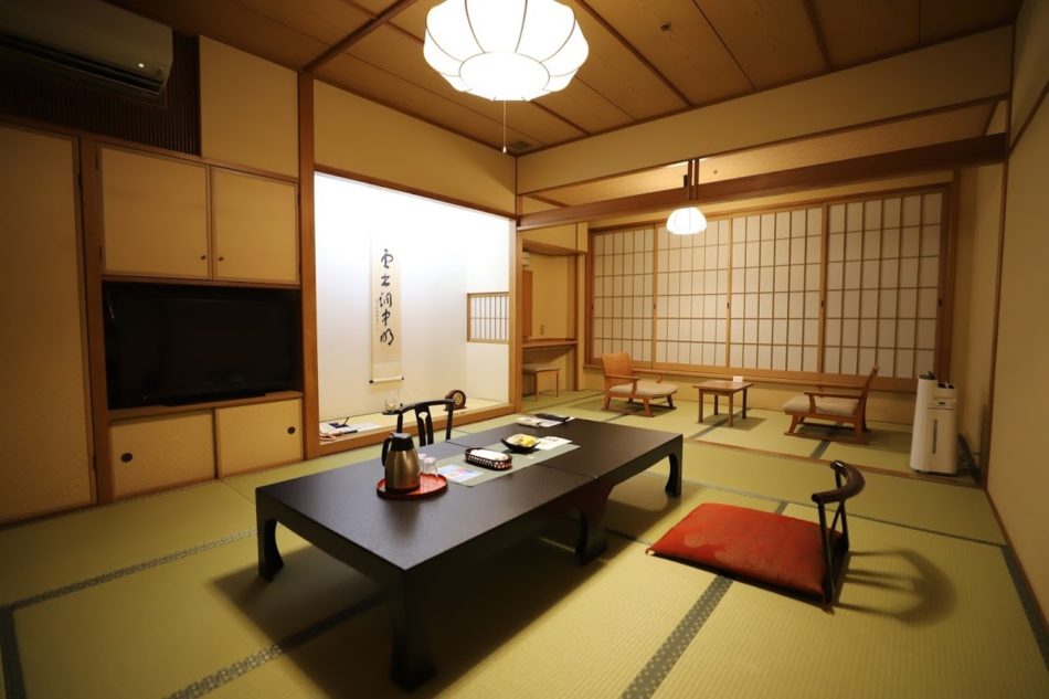 Traditional Japanese ryokan room with tatami floors, calligraphy scroll, and low table in Kochi, Japan