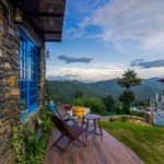 A beautiful heritage homestay wall with a mountain view and chair as greenery is seen of Stone Heritage Mukteshwar