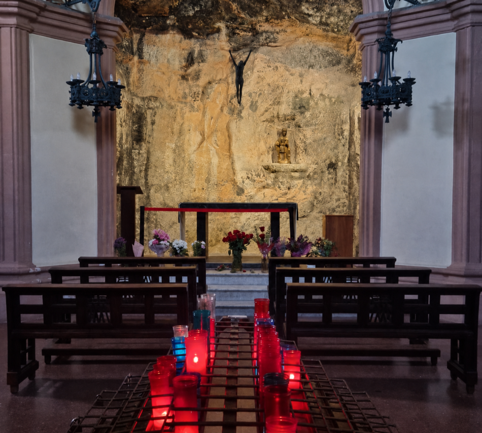 The interior of the Santa Cova chapel, with the altar built against the living rock and votive candles