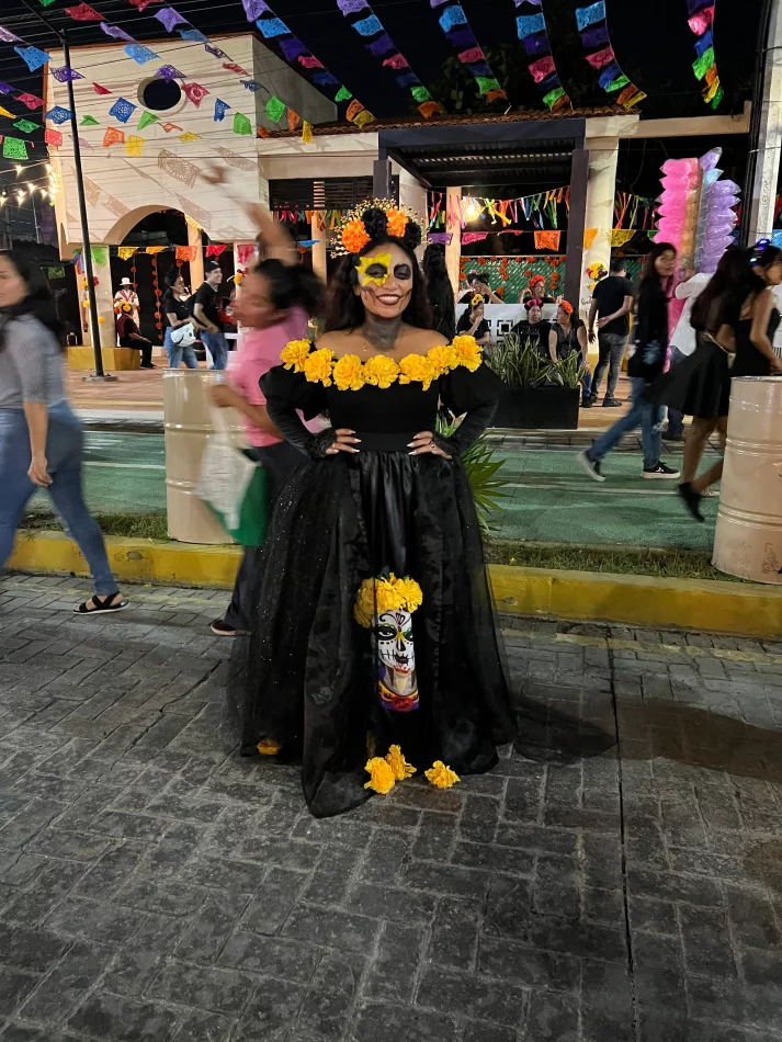 Woman in Catrina-style face paint and a black dress decorated with cempasúchil at the Day of the Dead/Hanal Pixán festival in Cancún.
